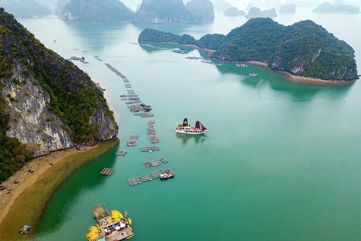 Karst islands, a beach and a floating fish farm seen from above on a Ha Long Bay junk boat cruise from Tuan Chau, Vietnam