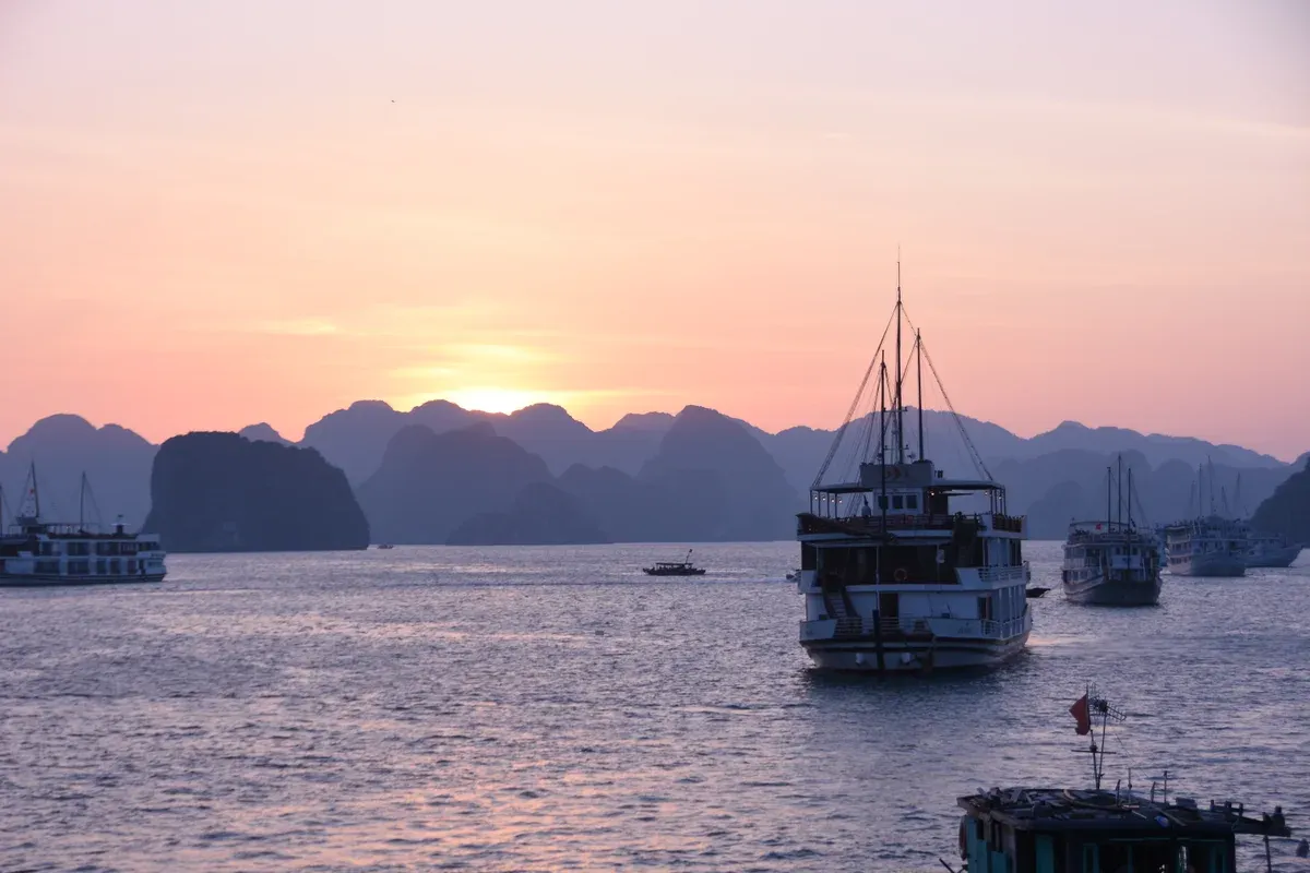 Cruise boats anchored at dusk among karsts on a Ha Long Bay junk boat cruise