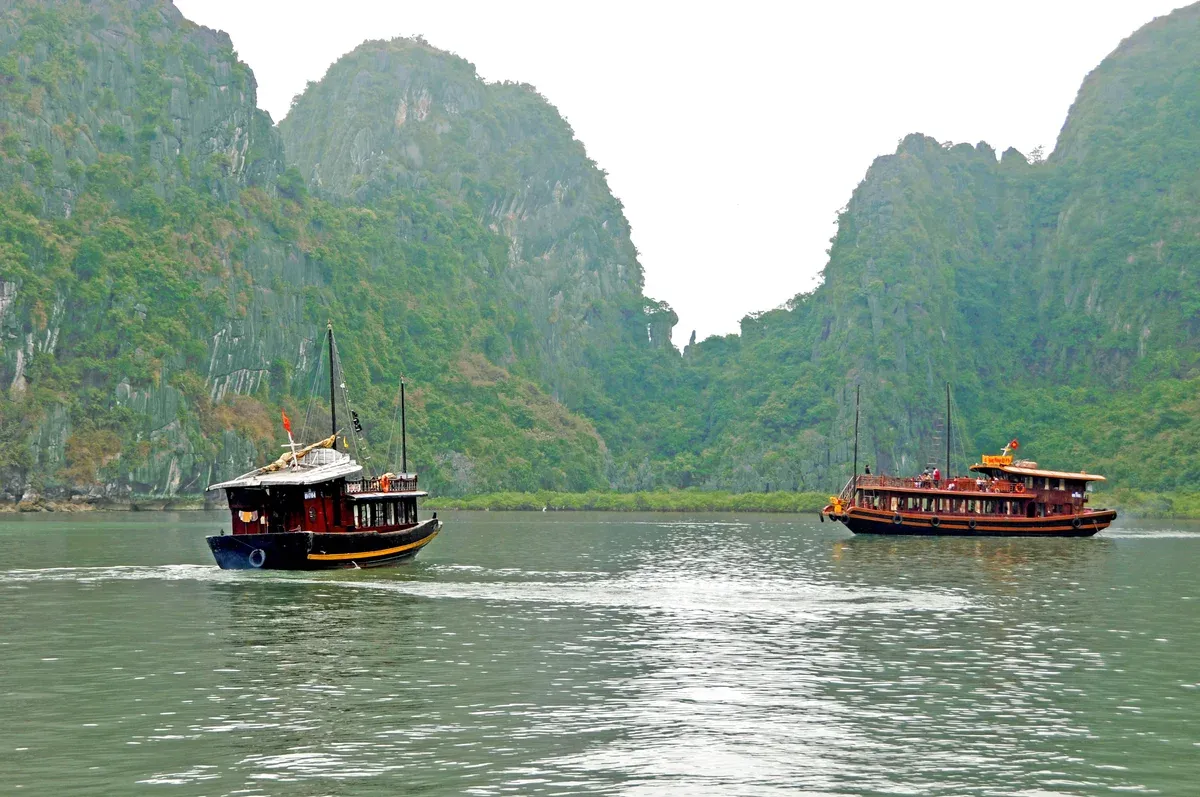 Junk-style cruise boats waiting off the Thien Cung Cave landing on a Ha Long Bay junk boat cruise
