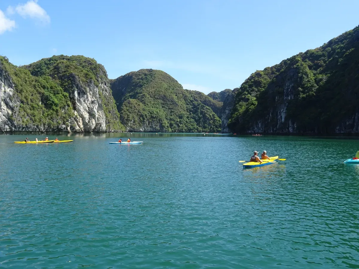 Kayakers paddling beside limestone karsts on a Ha Long Bay junk boat cruise