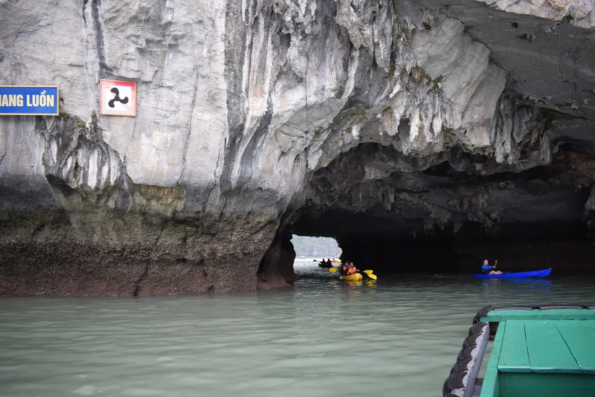 Kayaks passing through the Luon Cave archway on a Ha Long Bay junk boat cruise