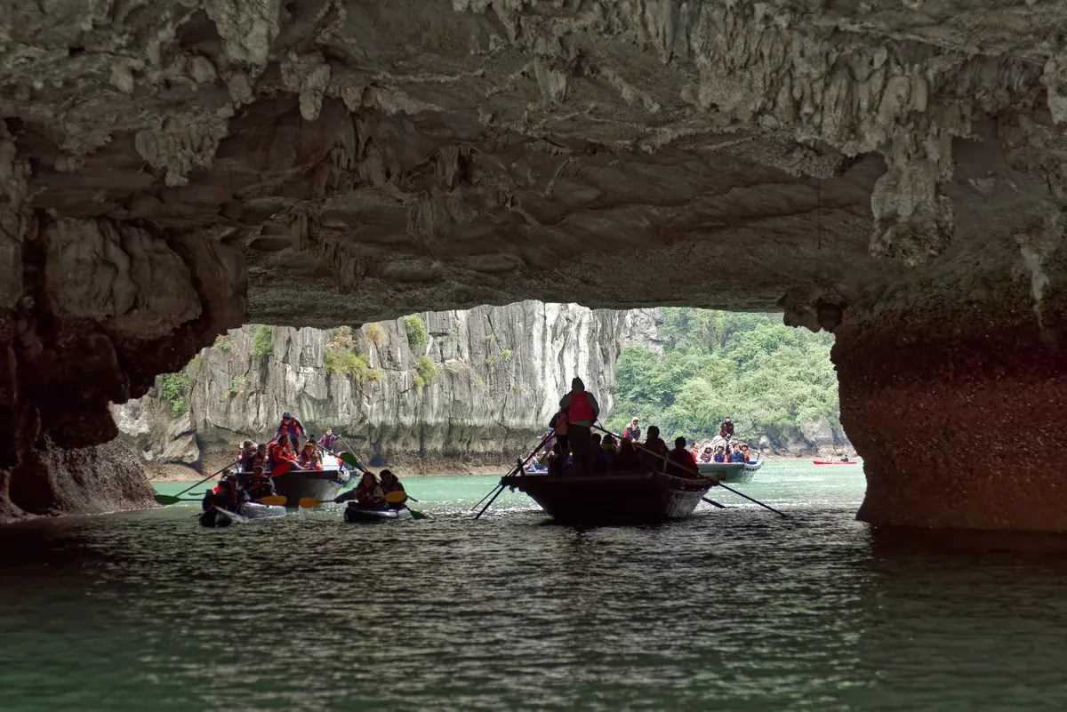 Rowing boats and kayaks passing through Luon Cave on a Ha Long Bay junk boat cruise